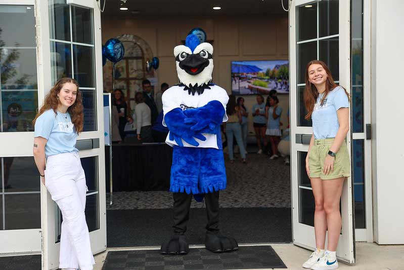 blue jay mascot in front of chapel